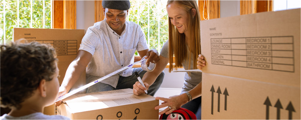 A family carefully packing and taping up moving boxes in their living room